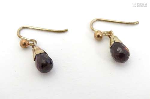 Yellow metal drop earrings set with facet cut garnet drops.