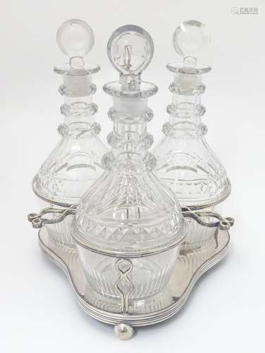 A 19thC silver plate 3-bottle decanter stand / tantalus containing a set of three cut glass