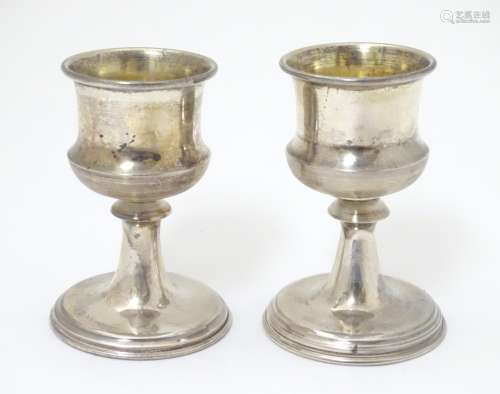 A pair of silver pedestal egg cups with gilded interiors.