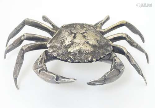 A white metal model of a crab, the body forming a small box with shell section hinging open.