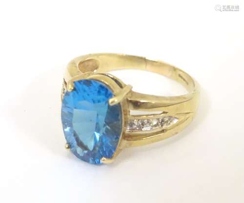 A 9ct gold ring set with central topaz flanked by white stones to shoulders.