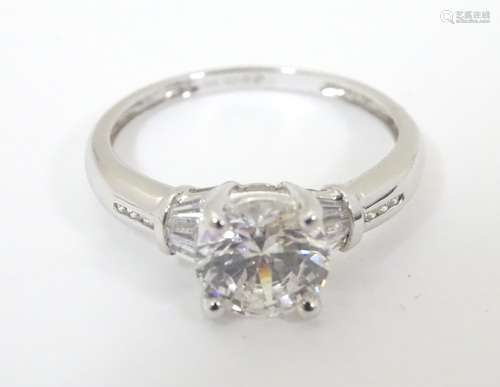 A 14ct white gold ring set with central cubic zirconia flaked by further stones to shoulders.