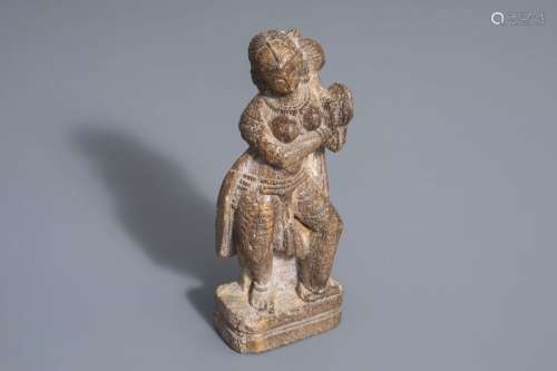 A stone figure of a female musician with cymbals, ...
