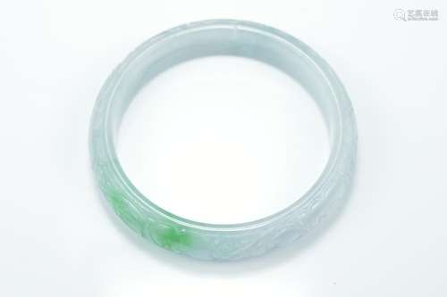 A Chinese carved jadeite bangle in pale white and green