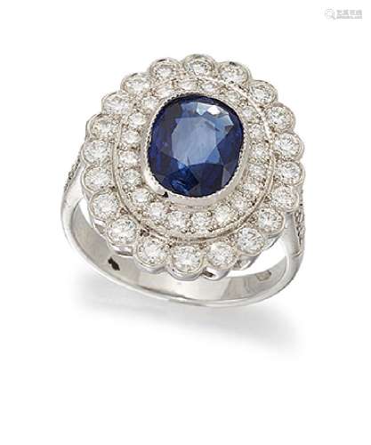 A sapphire and diamond cluster ring, the collet-set oval sapphire to brilliant-cut diamond two row