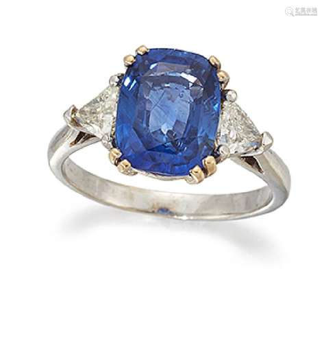 A sapphire and diamond three stone ring, the cushion shaped sapphire centre between triangular-cut