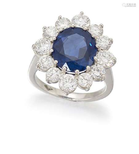 A sapphire and diamond cluster ring, the central oval-shaped sapphire within a brilliant-cut diamond