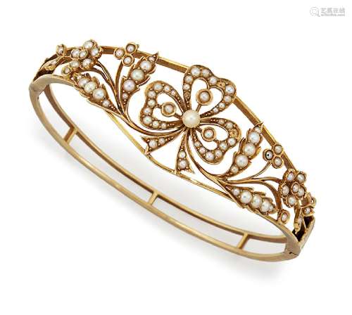 An Edwardian gold and half-pearl bangle, of hinged open hoop design, the tapered front with