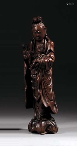 STATUETTE DE GUANYIN en bois naturel, représentée en pied, déversant de la main gauche le contenu du vase à eau lustrale et la main ...