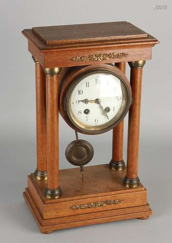 Antique oak pedestal clock with brass decorations.