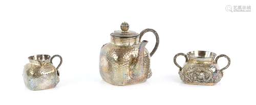 A Chinese, or other Asian, hammered white metal teapot, sugar bowl, and cream jug; each one