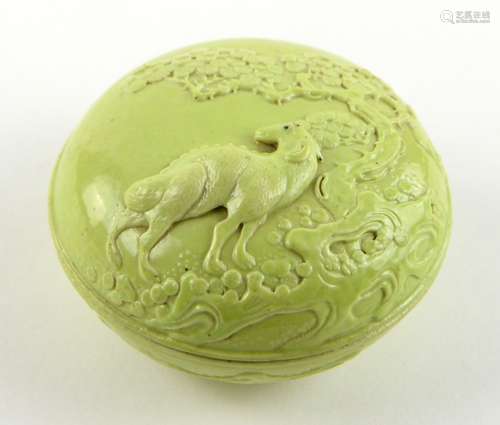 A lime green monochrome circular box and cover, decorated in high relief with a ram beside a pine