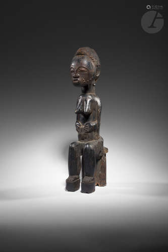 Une statuette féminine assise, le visage et le corps scarifiés, et la coiffe finement ciselée,