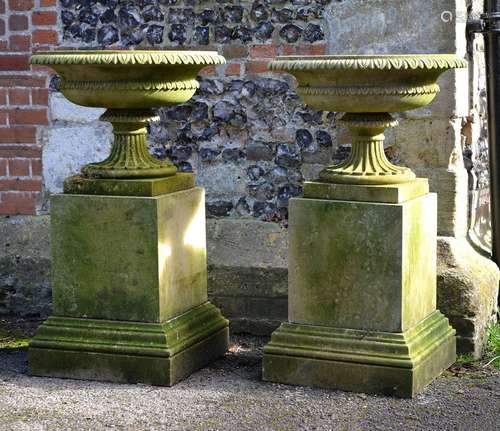 A pair of English carved limestone urns on plinths