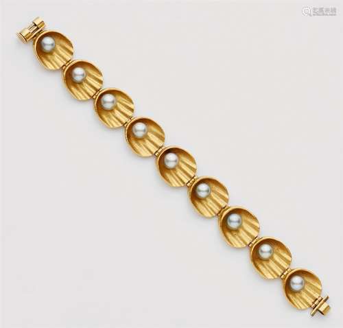 An 18k gold and pearl bracelet18k gold bracelet designed as a strand of stylised scallop motifs with