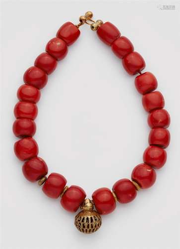 An African gold and coral necklaceDesigned as a strand of 22 graduated drum-shaped coral beads (