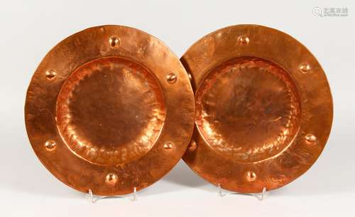 A PAIR OF ARTS & CRAFTS CIRCULAR DISHES, with embossed decoration. 13ins diameter.