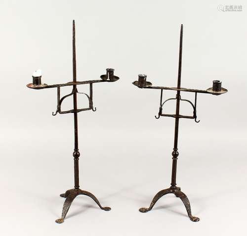 TWO 18TH/19TH CENTURY WROUGHT IRON CANDLESTICKS, on tripod bases. 23ins high.