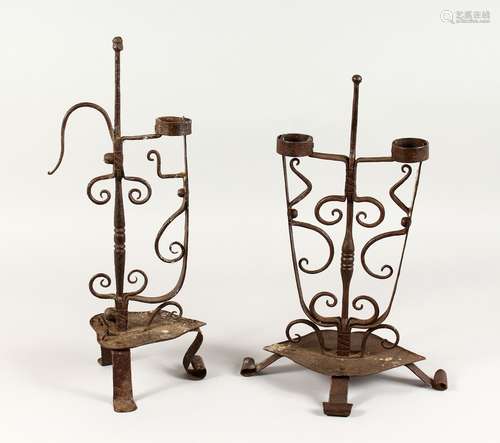 TWO 18TH/19TH CENTURY WROUGHT IRON CANDLESTICKS, on scrolling feet. 17.5ins and 19ins high.