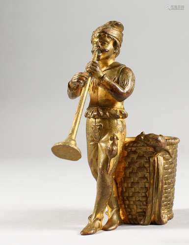 AN ORMOLU MATCH HOLDER, modelled as The Pied Piper, a man standing by a basket playing a pipe.