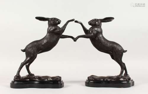 A SMALL PAIR OF BRONZE BOXING HARES, on shaped marble bases.
