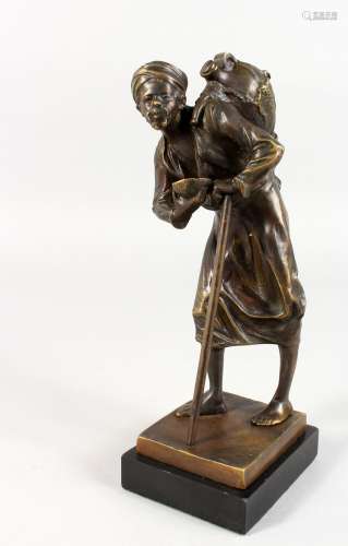 A GOOD BRONZE OF AN ARAB, pitcher on his back, walking with a stick. 9.5ins high.