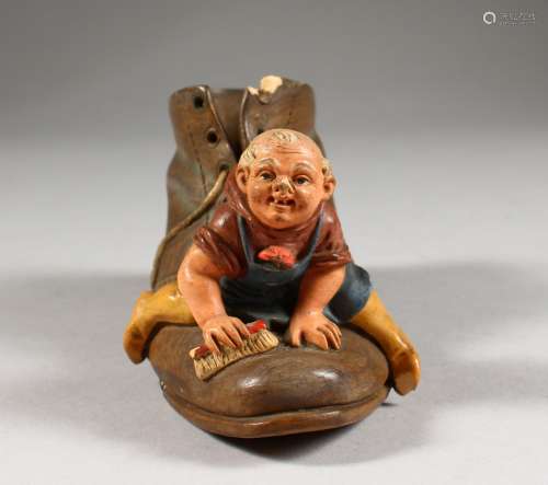 A CONTINENTAL PAINTED TERRACOTTA GROUP OF A MAN ON A SHOE. 5ins high.