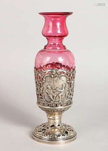 A STERLING SILVER AND RUBY GLASS VASE, repousse with Dutch scenes.