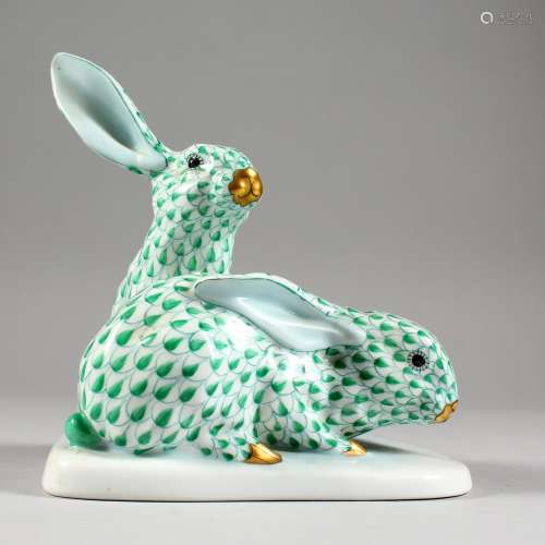 A HEREND PORCELAIN GROUP OF TWO RABBITS, seated on a shaped base. 5.5ins high.