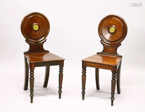 A GOOD PAIR OF REGENCY MAHOGANY HALL CHAIRS, the circular backs with painted crests, solid seats