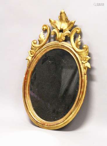 A 19TH CENTURY OVAL GILT FRAMED MIRROR, with carved cresting. 2ft 10.5ins high x 1ft 9ins wide.