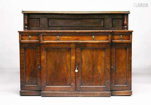 A REGENCY MAHOGAN BREAKFRONT SIDEBOARD, the gallery top with a brass rail, over a long frieze drawer