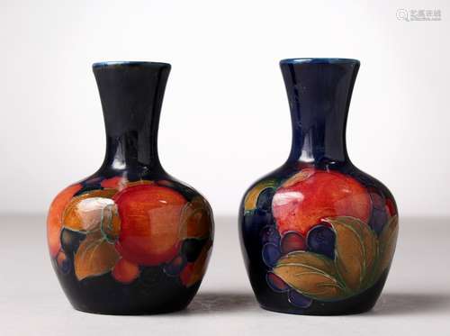 A NEAR PAIR OF SMALL MOORCROFT POTTERY BULBOUS VASES, pomegranate and fruit, blue ground. W.