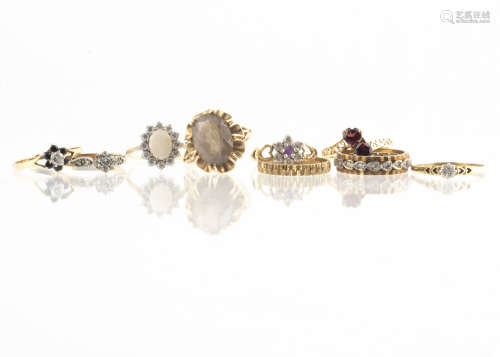 Nine 9ct gold rings, including a textured band, two illusion set diamond solitaires, a garnet