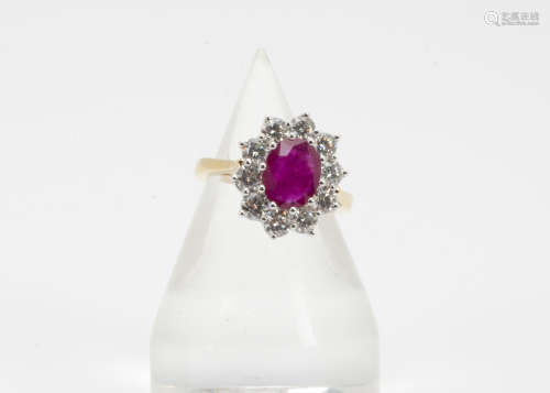 A ruby and diamond 18ct gold cluster ring, the oval mixed cut ruby in claw setting surrounded by a