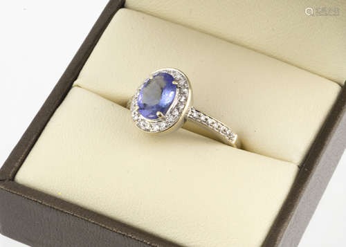 A 9ct gold tanzanite and diamond cluster ring, the oval mixed cut claw set blue tanzanite surrounded