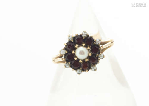 A contemporary garnet and pearl yellow metal cluster ring, the central claw set pearl surrounded