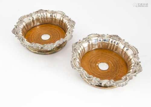 A pair of early 20th Century silver plated wine bottle coasters, in the Georgian taste with rococo