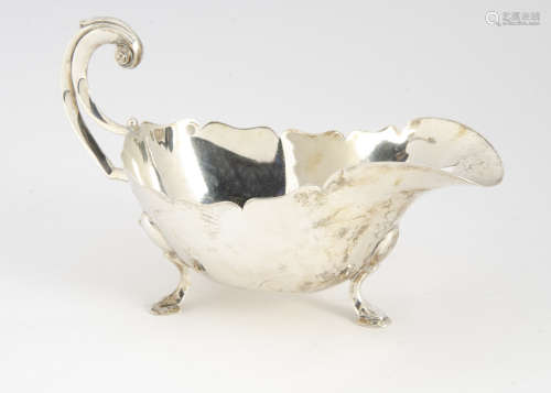 A George V silver sauce boat from Sir JBL Ltd, on three supports with shaped rim and C scroll