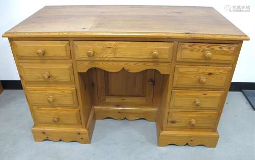 A contemporary pine knee hole desk, moulded top, a long central drawer flanked by four short drawers