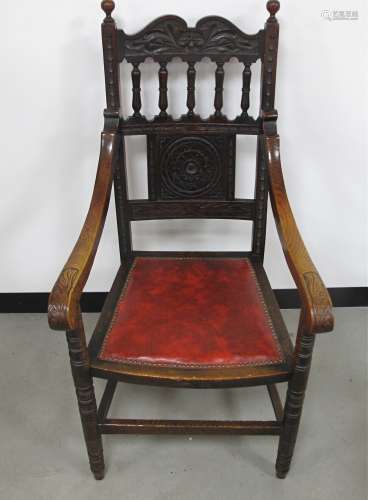 A late 19th Century oak and elm elbow chair, with carved back panel and rail, red studded upholstery