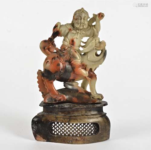 A 19th Century Chinese soapstone carved figure, modelled as a seated warrior upon a mythical