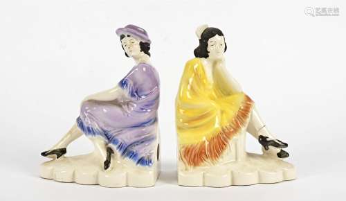 A pair of continental Art Deco pottery bookends, modelled as seated fashionable ladies, one in a