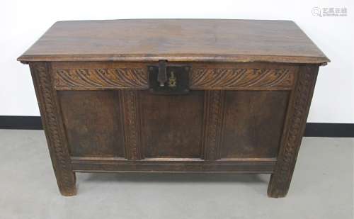 An 18th Century oak coffer, the top with a moulded edge, with three panels surrounded by carved