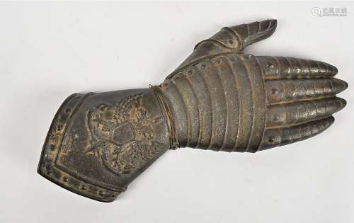 A metalwork hand taking the form of a Knight's gauntlet, with chivalric decoration of griffins above