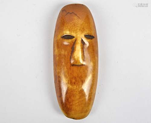 A Lega ivory mask, Congo, coloured with dark patina, modelled as a face, length 11cm