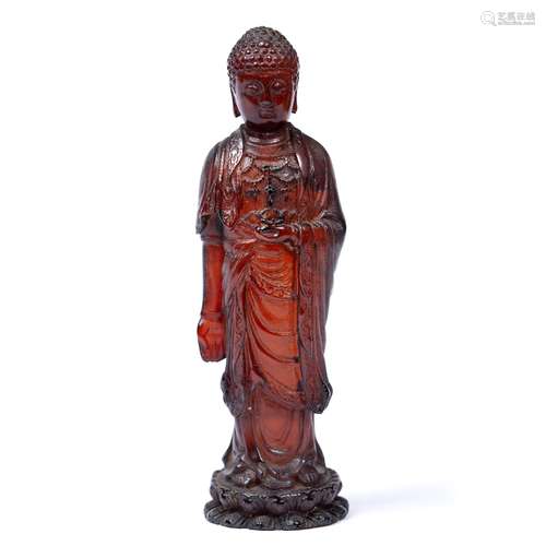 Red ambroid figure of a standing Buddha Chinese, 19th Century holding a flower in the palm of the