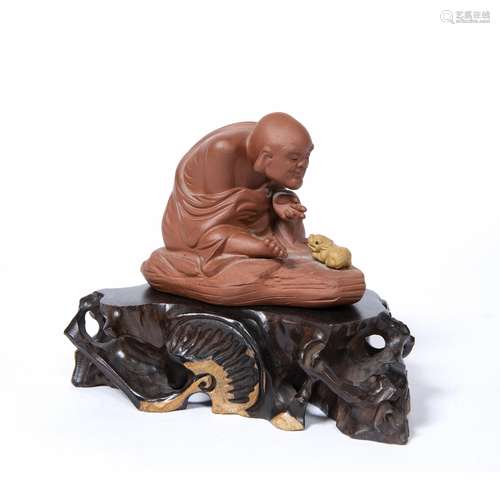 Yixing figure of a man Chinese, 20th Century depicting a figure crouching over a baby kirin, by Li