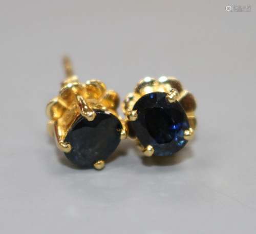 A pair of yellow metal (stamped 18k) and solitaire oval cut sapphire set eat studs, sapphires