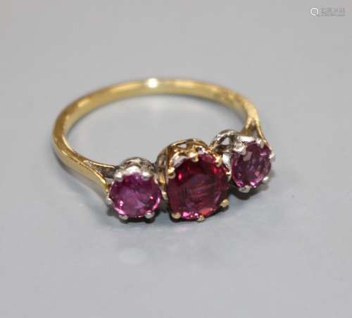 An 18ct and three stone ruby set dress ring, size M, gross 2.7 grams. Condition: Two outer stones